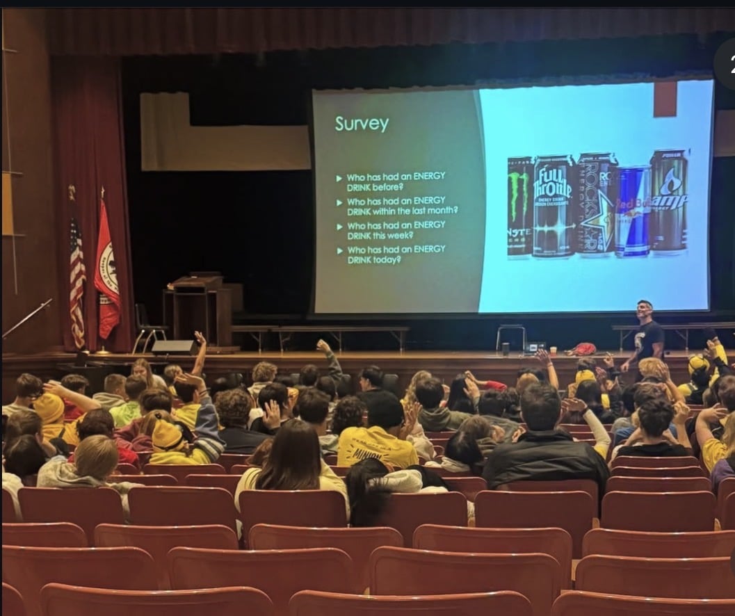 Chris Sargent presenting to a packed high school auditorium