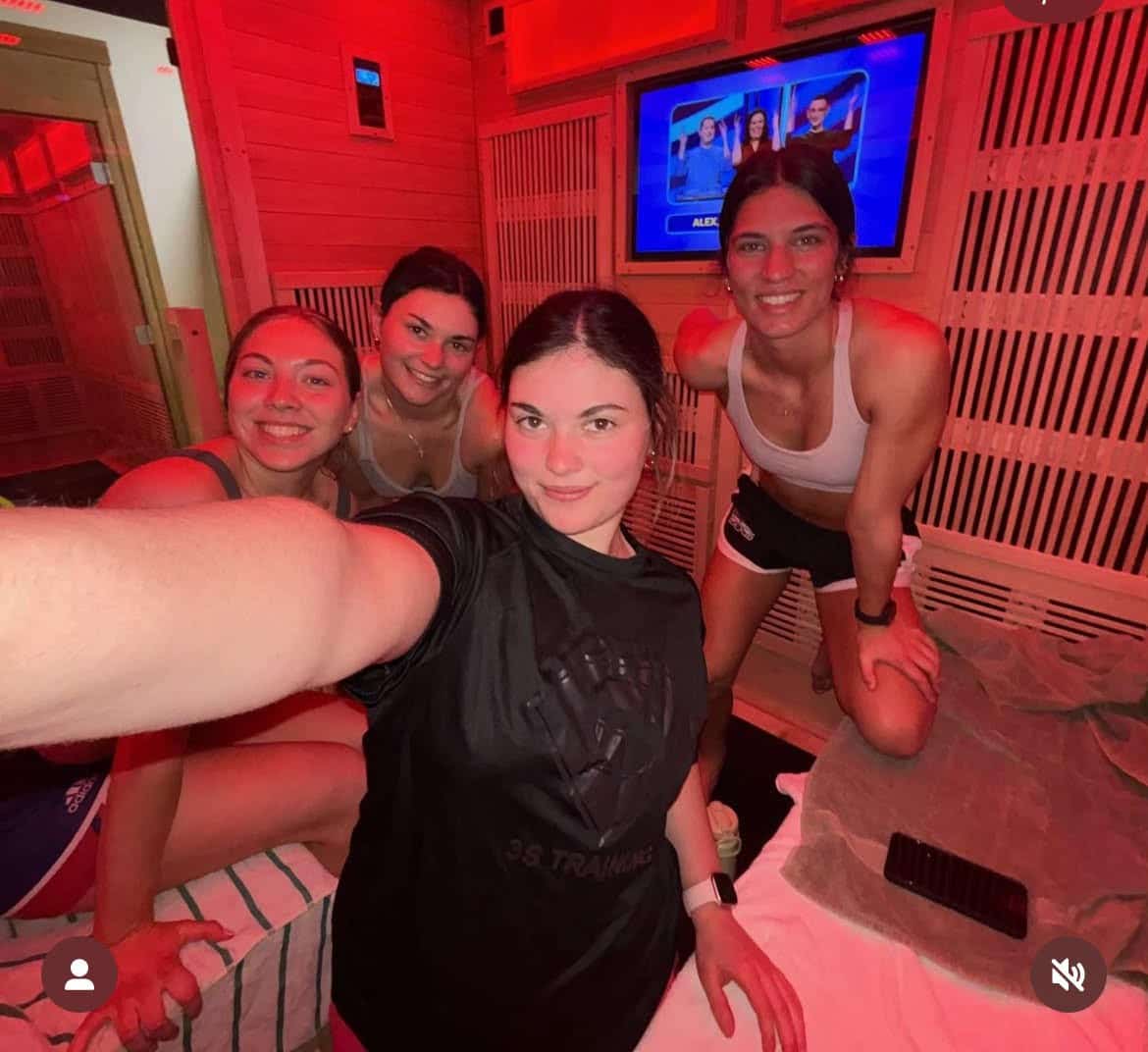 Four athletes smiling inside a Hot Box infrared sauna