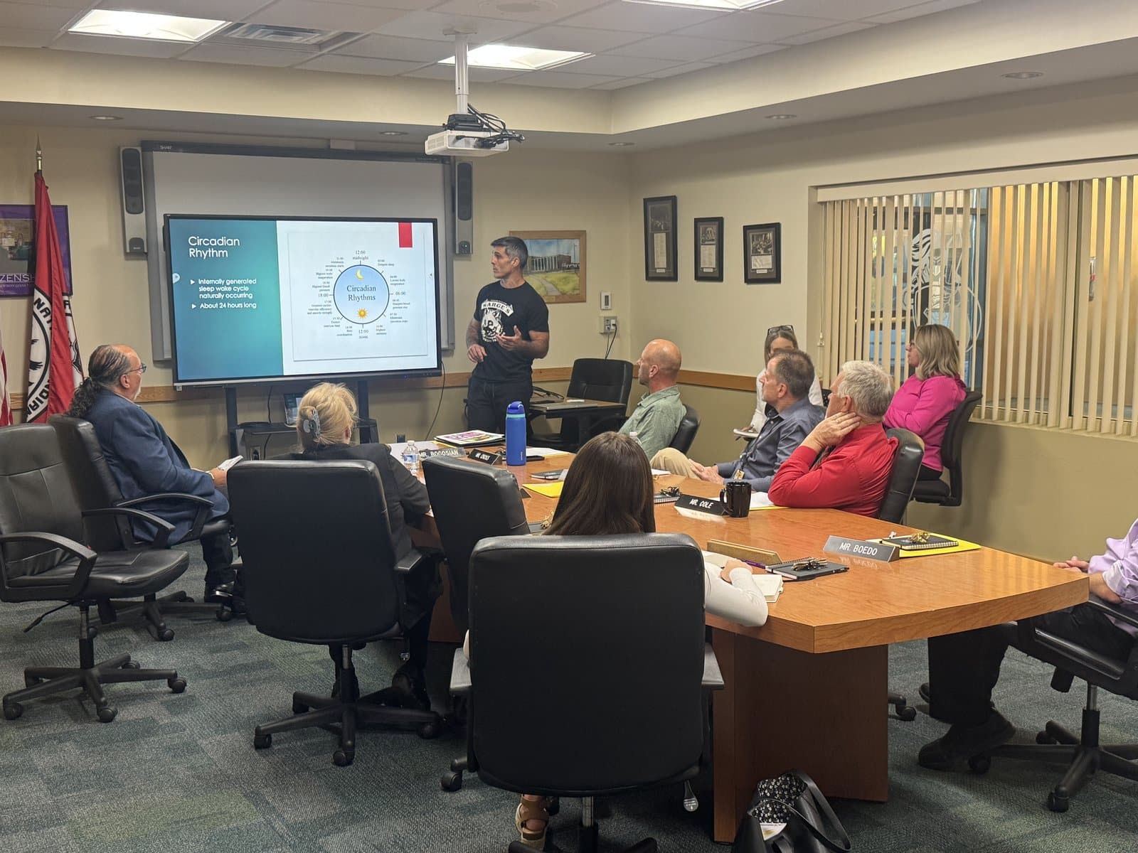 Chris Sargent presenting on circadian rhythm to a board of adults around a conference table